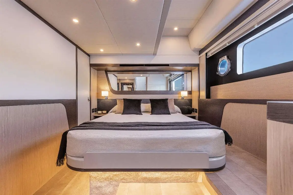 Modern yacht interior featuring a double bed, stylish lamps, and circular window, designed for luxury and comfort.